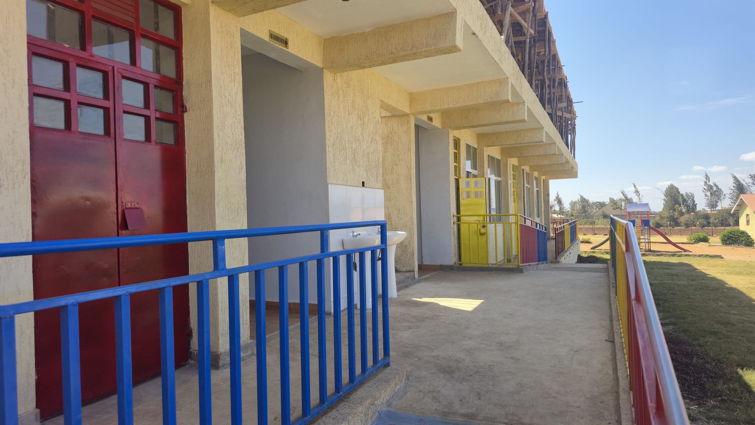 A covered walkway with blue safety railings running past Oak Leaf Academy lower primary classrooms.